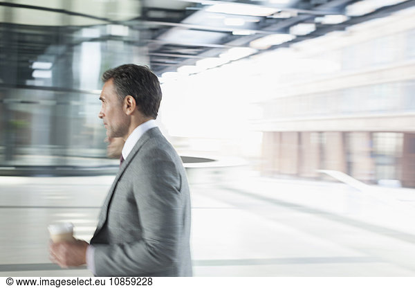 Corporate businessman with coffee walking outdoors
