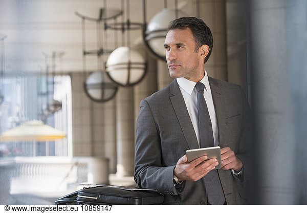 Corporate businessman with digital tablet looking away