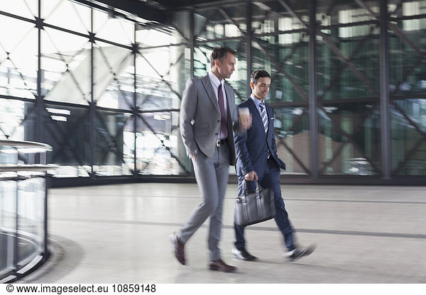 Corporate businessmen walking in modern lobby
