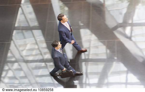 Corporate businessmen walking in modern office lobby