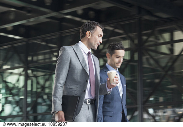 Corporate businessmen with coffee talking and walking