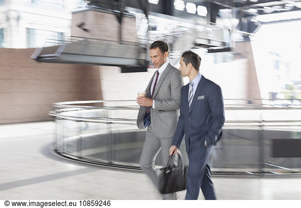 Corporate businessmen with coffee walking and talking