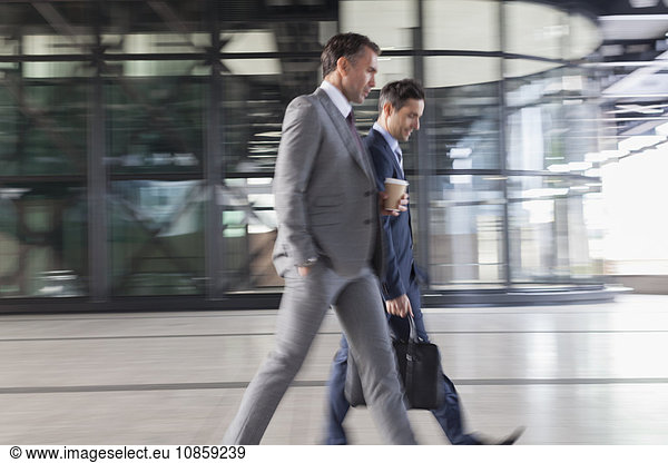 Corporate businessmen with coffee walking outside building