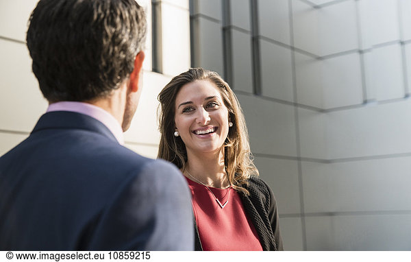 Corporate businesswoman smiling and talking to businessman