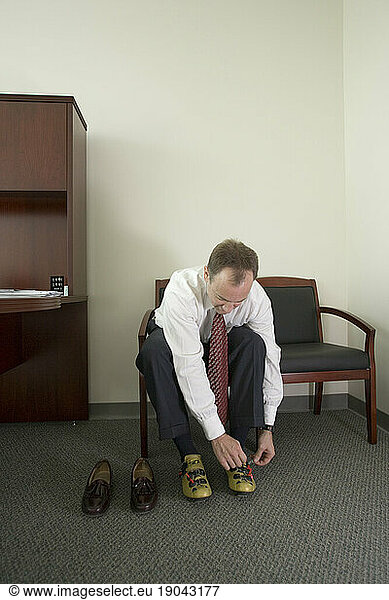 Corporate executive puts on his bicycle shoes in his office  Santa Clara  California.
