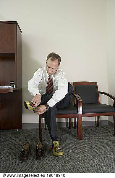 Corporate executive puts on his bicycle shoes in his office  Santa Clara  California.