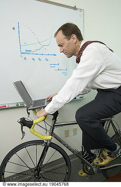 Corporate executive works out on his bicycle trainer as he works in his office in Santa Clara  California.