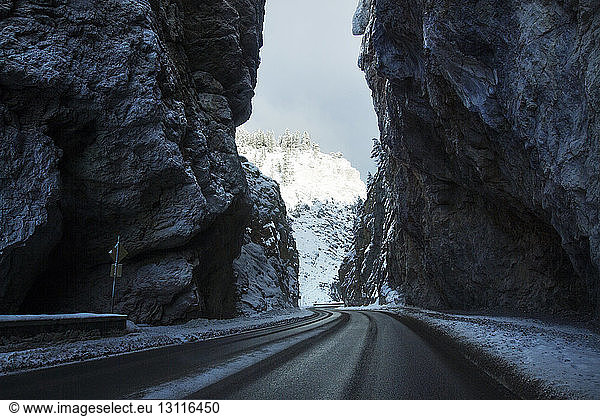 Country road amidst mountains during winter
