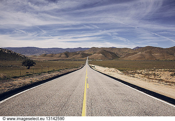 Country road leading towards mountains at Death Valley National Park against sky