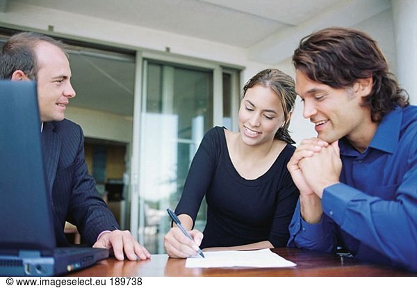 Couple and financial adviser signing paperwork