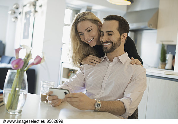 Couple at home looking at pictures on smartphone