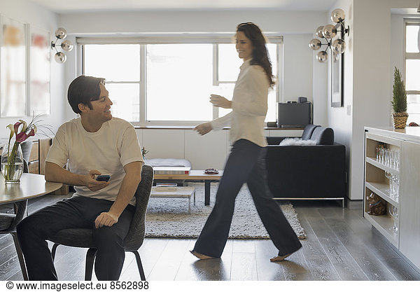 Couple at Home  Man using smartphone  Woman walking past