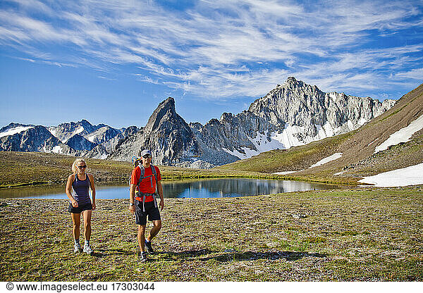 couple backpacking in scenic alpine meadow  mountains behind.