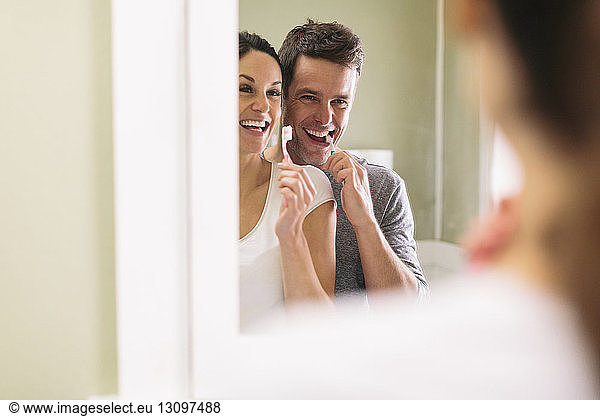 Couple brushing teeth while reflecting in mirror