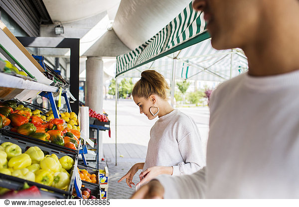 Couple buying fruits and vegetables at market stall