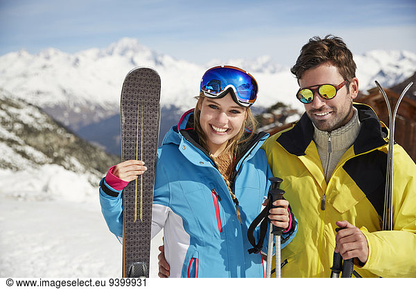 Couple carrying skis on mountain top