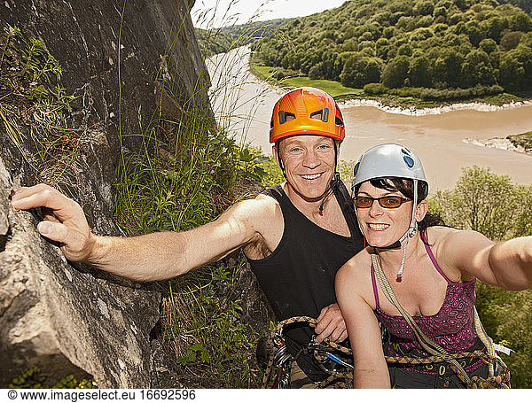 couple climbing steep rock face in south Wales