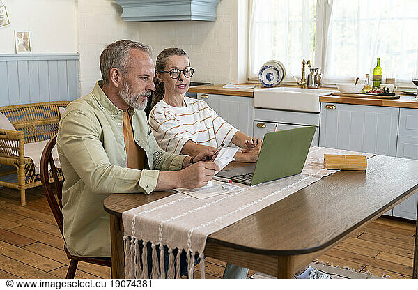 Couple discussing over financial bills sitting at table at home