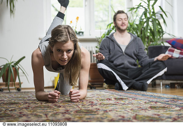 Couple doing exercise in living room  Munich  Bavaria  Germany