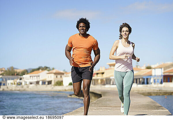 Couple doing running exercise on pier near sea in coastal area