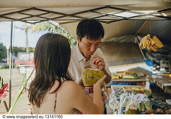 Couple drinking coconut water at market stall
