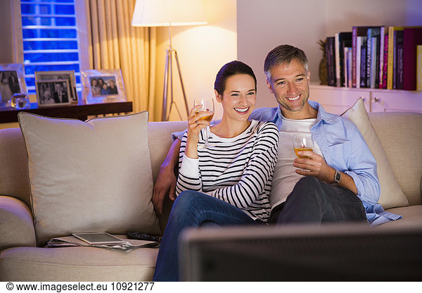 Couple drinking wine and watching TV in living room