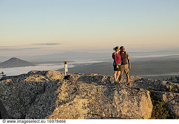 Couple embraces and hug after reaching summit of mountain in Maine