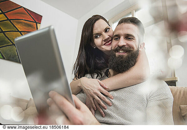 Couple embracing and watching digital tablet