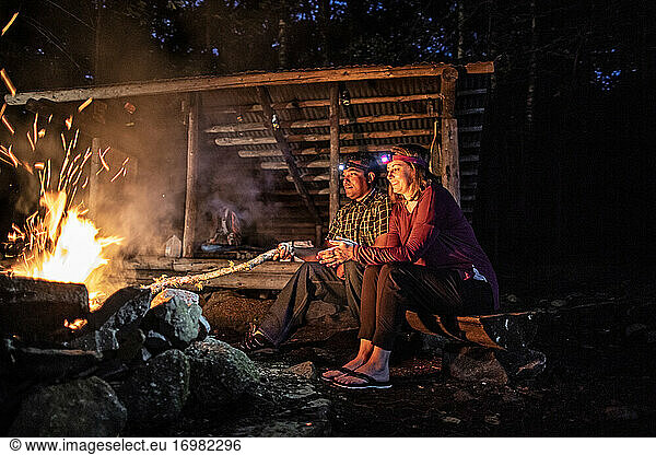 Couple enjoy warmth from campfire at Appalachian Trail lean to  Maine