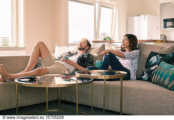 Couple enjoying coffee while resting on sofa in apartment