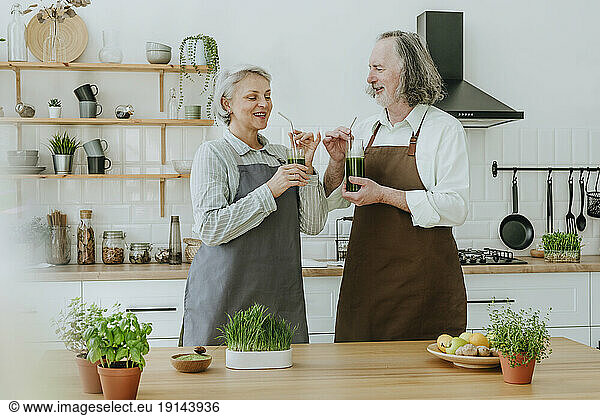 Couple enjoying healthy detox juice standing in kitchen at home