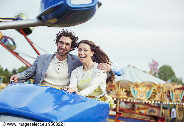 Couple enjoying ride on carousel in amusement park