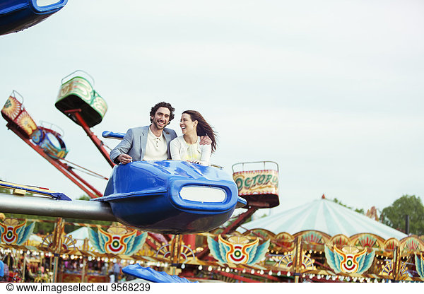 Couple enjoying ride on carousel in amusement park