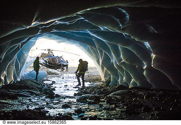 Couple exploring ice cave during helicopter tour.