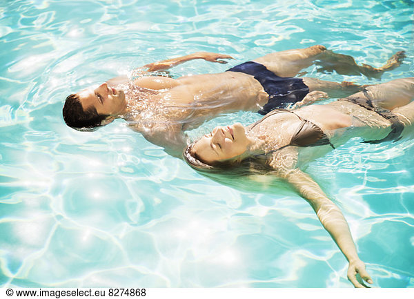 Couple floating in swimming pool