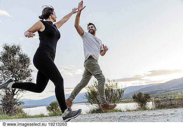 Couple giving high-five and running on footpath