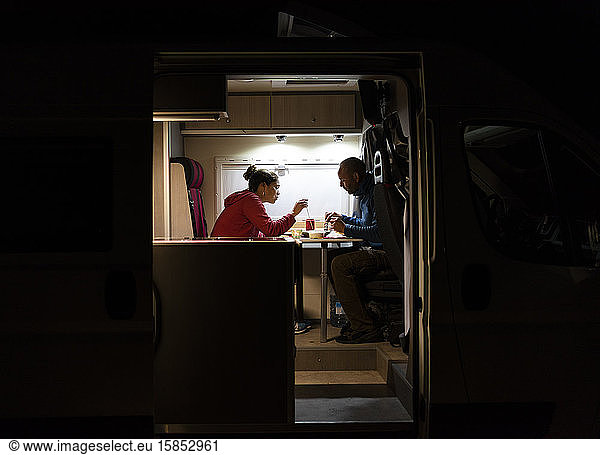 Couple having a relaxed dinner in a motorhome during a trip.