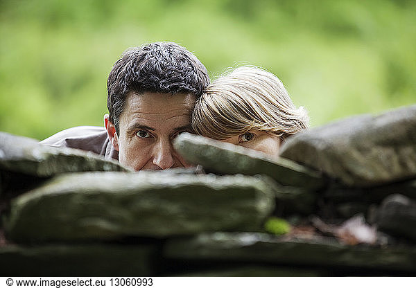 Couple hiding behind stone wall