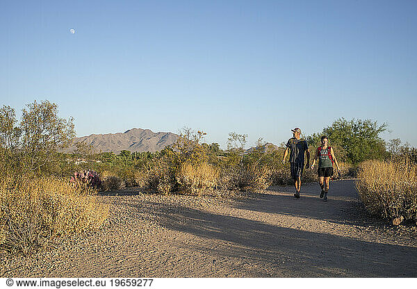 Couple hiking desert nature trail under day moon