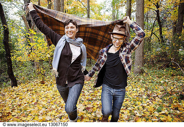 Couple holding blanket while walking on field