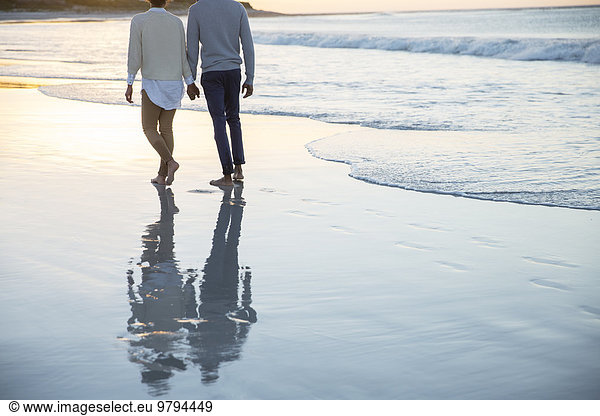Couple holding hands and walking on beach