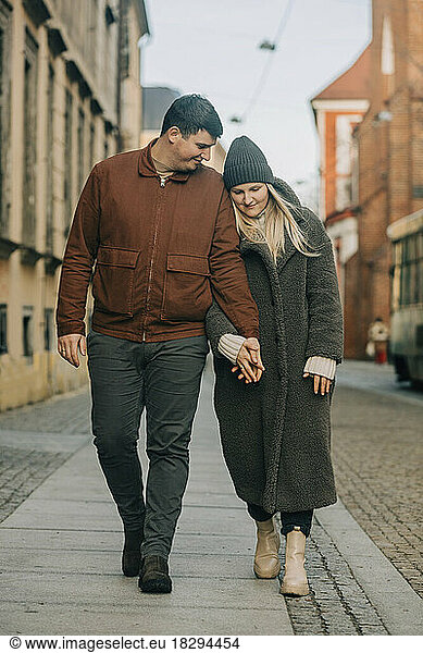 Couple holding hands and walking on footpath