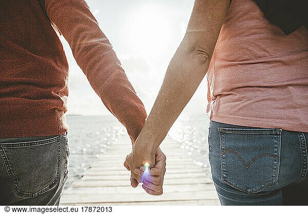 Couple holding hands at beach on sunny day