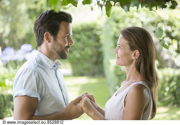Couple holding hands face to face in garden