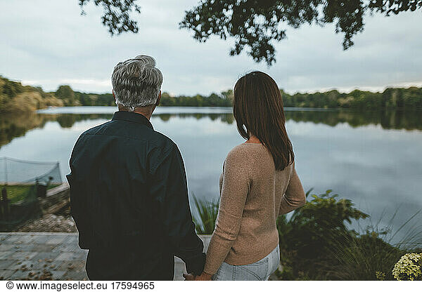 Couple holding hands standing by lake