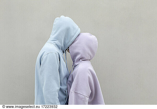 Couple in hooded shirt kissing by wall Couple in hooded shirt kissing ...