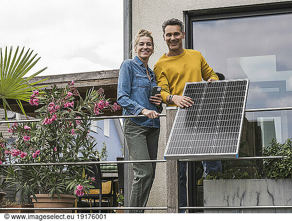 Couple installing solar panel on balcony