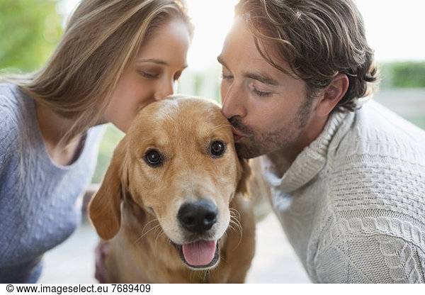 Couple kissing dog indoors