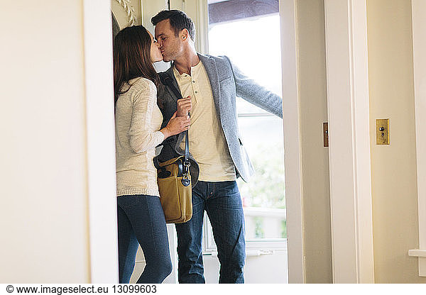Couple kissing while standing at doorway