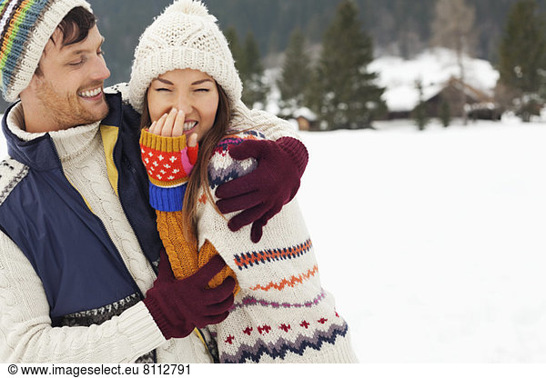 Couple laughing and hugging in snowy field